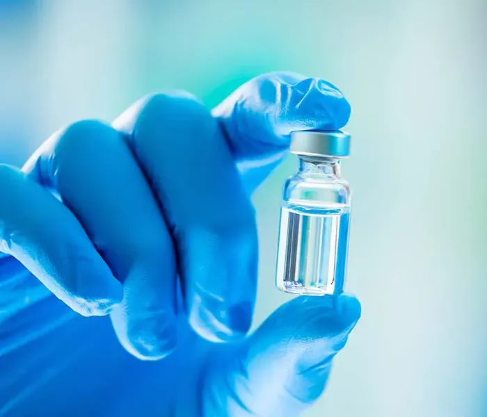 Gloved hand holding a vaccine vial