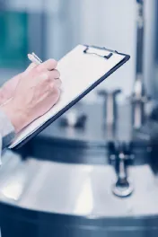 Closeup of hand writing on clipboard in a cleanroom environment