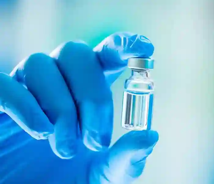 Gloved hand holding a vaccine vial