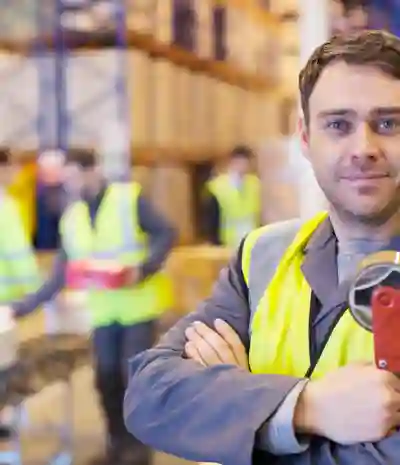 Warehouse worker smiling, on a background of warehouse racks and coworkers unloading boxes onto a conveyor belt