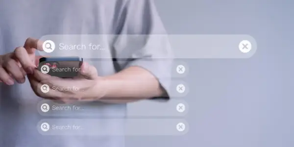 Man in t-shirt browsing products on a cellphone, on a grey background, with a transparent search bar as an overlay to the background image.