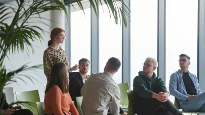 A diverse group of business professionals sits attentively in a modern office, actively participating in a training session led by an instructor, focusing on the latest technological advancements in the business world. - Stockbeeld