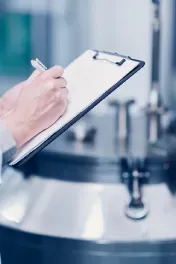 Closeup of hand writing on clipboard in a cleanroom environment